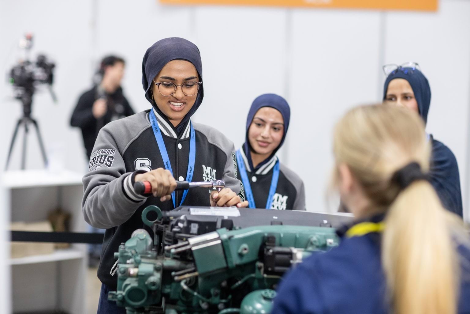 Female students trying out mechanics on an engine
