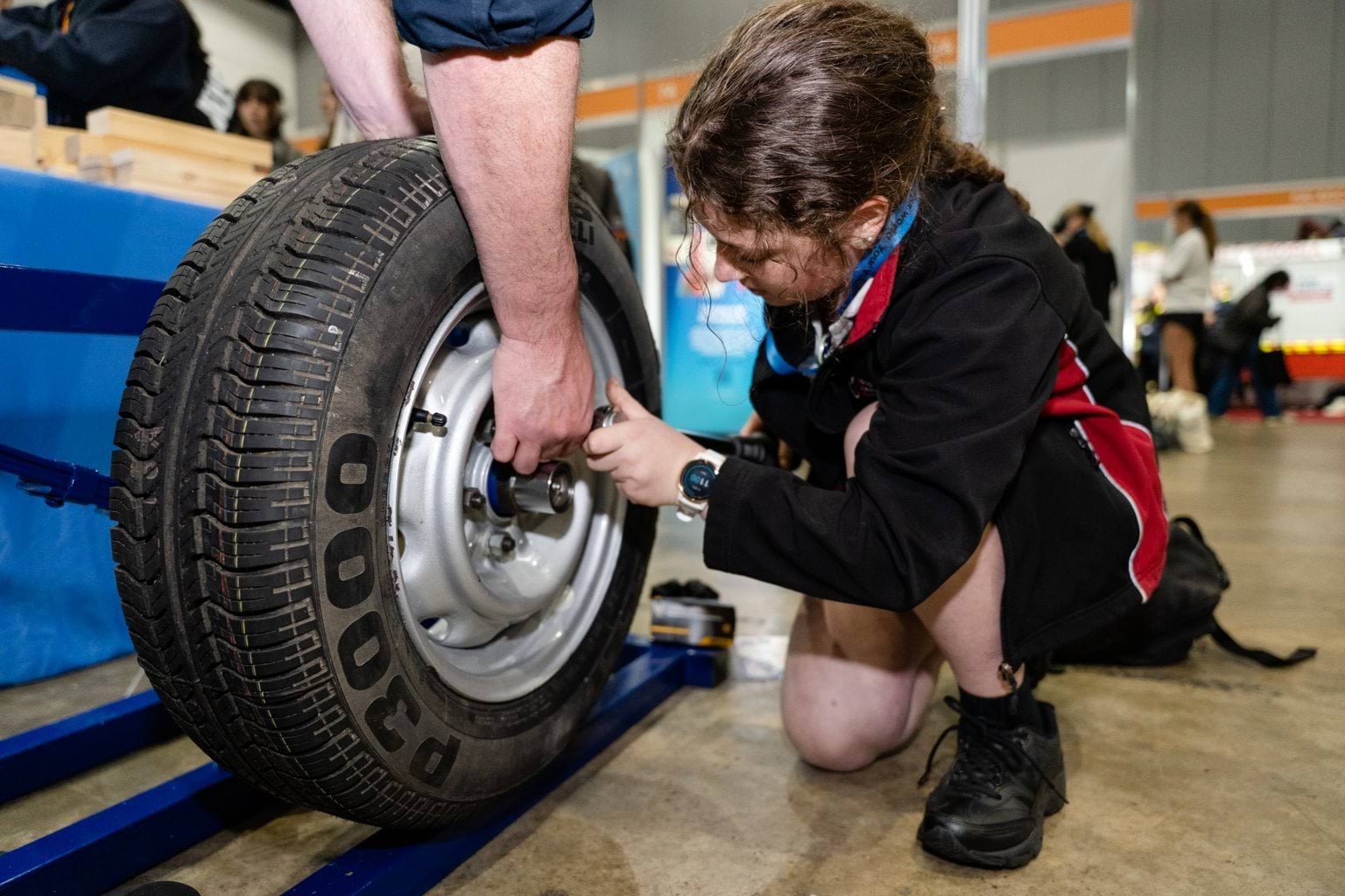 Female student tightening screws on car wheel