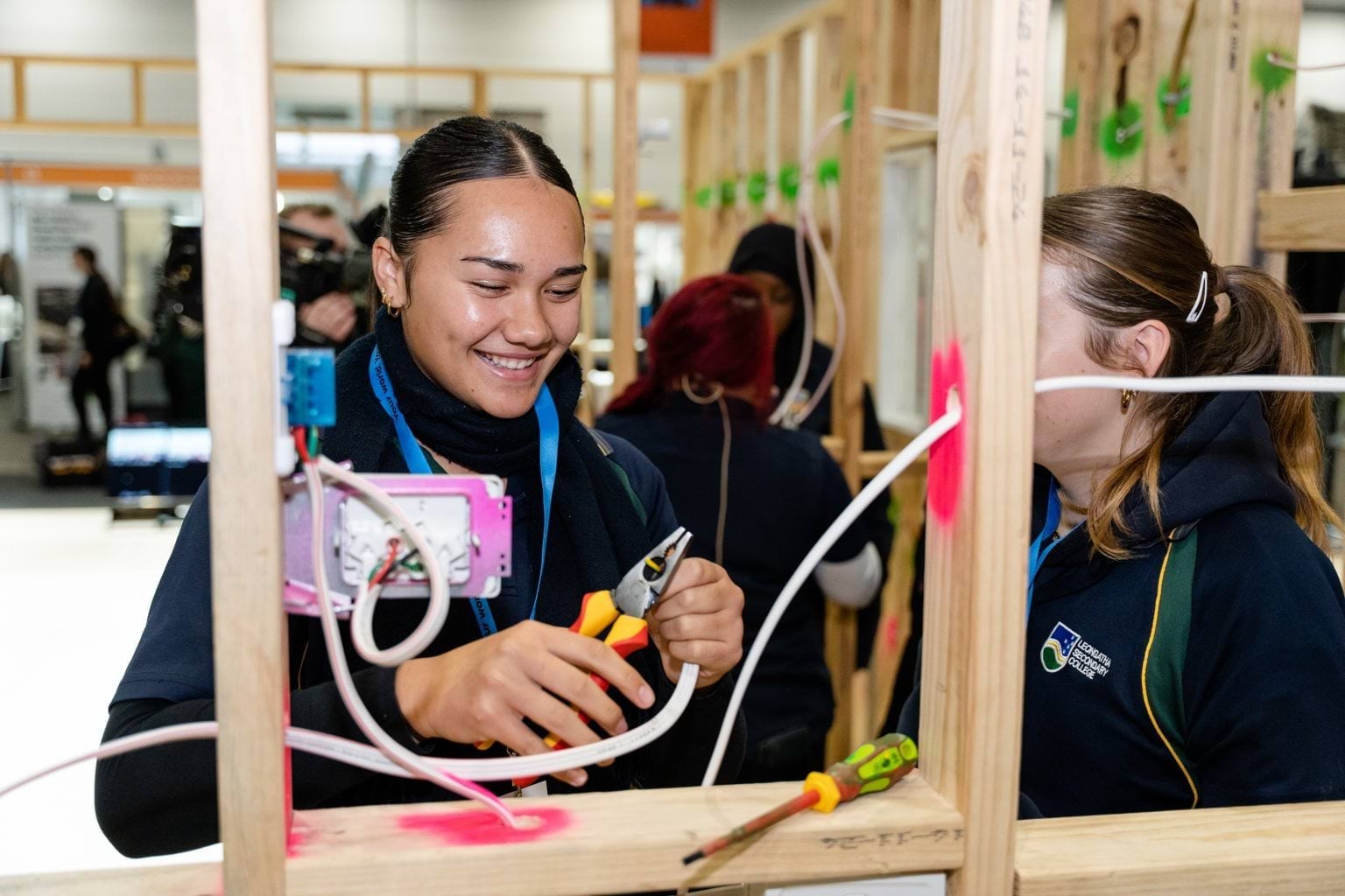 Female students wiring a house frame