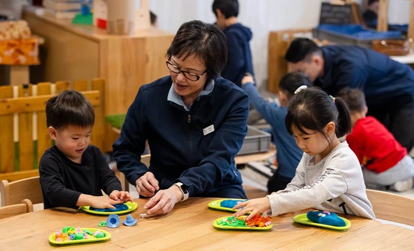 An educator assisting children working on a craft
