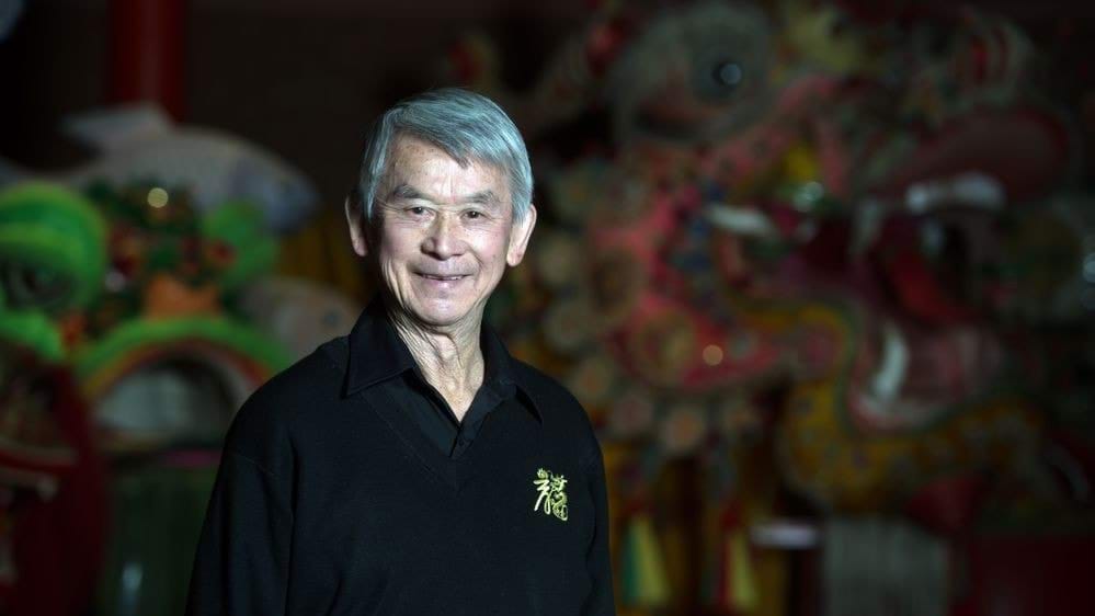A portrait of Russell Jack AM smiling while standing in front of an imperial dragon