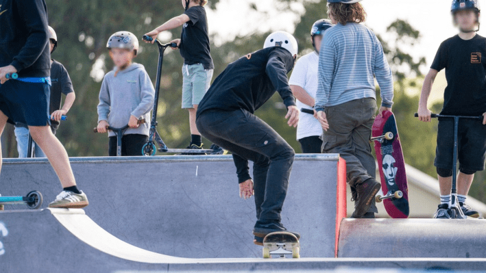 A group of teenagers on skateboards at the skate park