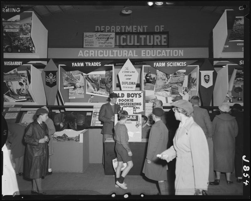 Black and white photo of people walking past a display that says Department of Agriculture