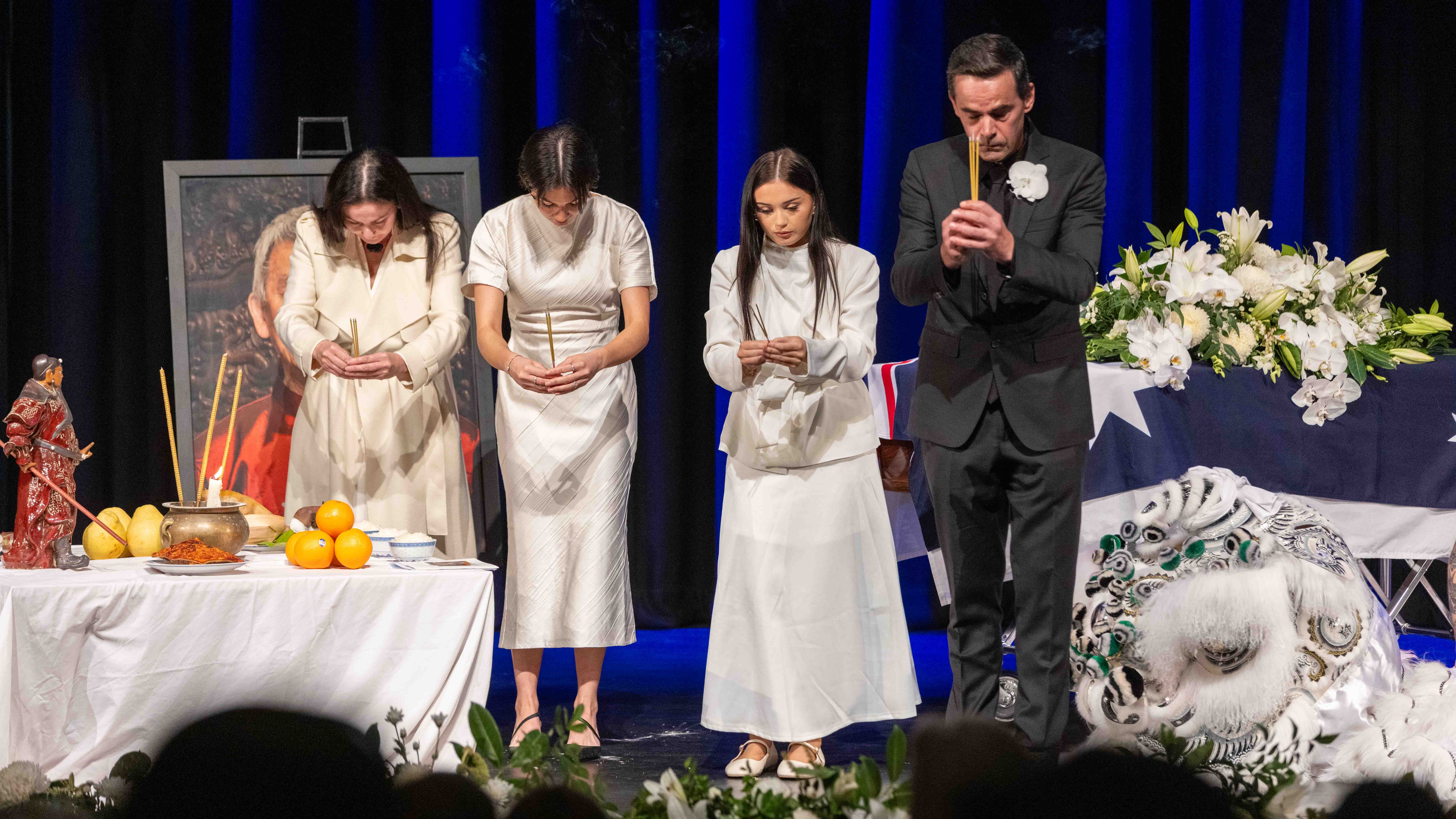 Russell's daughter, granddaughters and son-in-law stand on stage at the State Funeral Service and offer joss