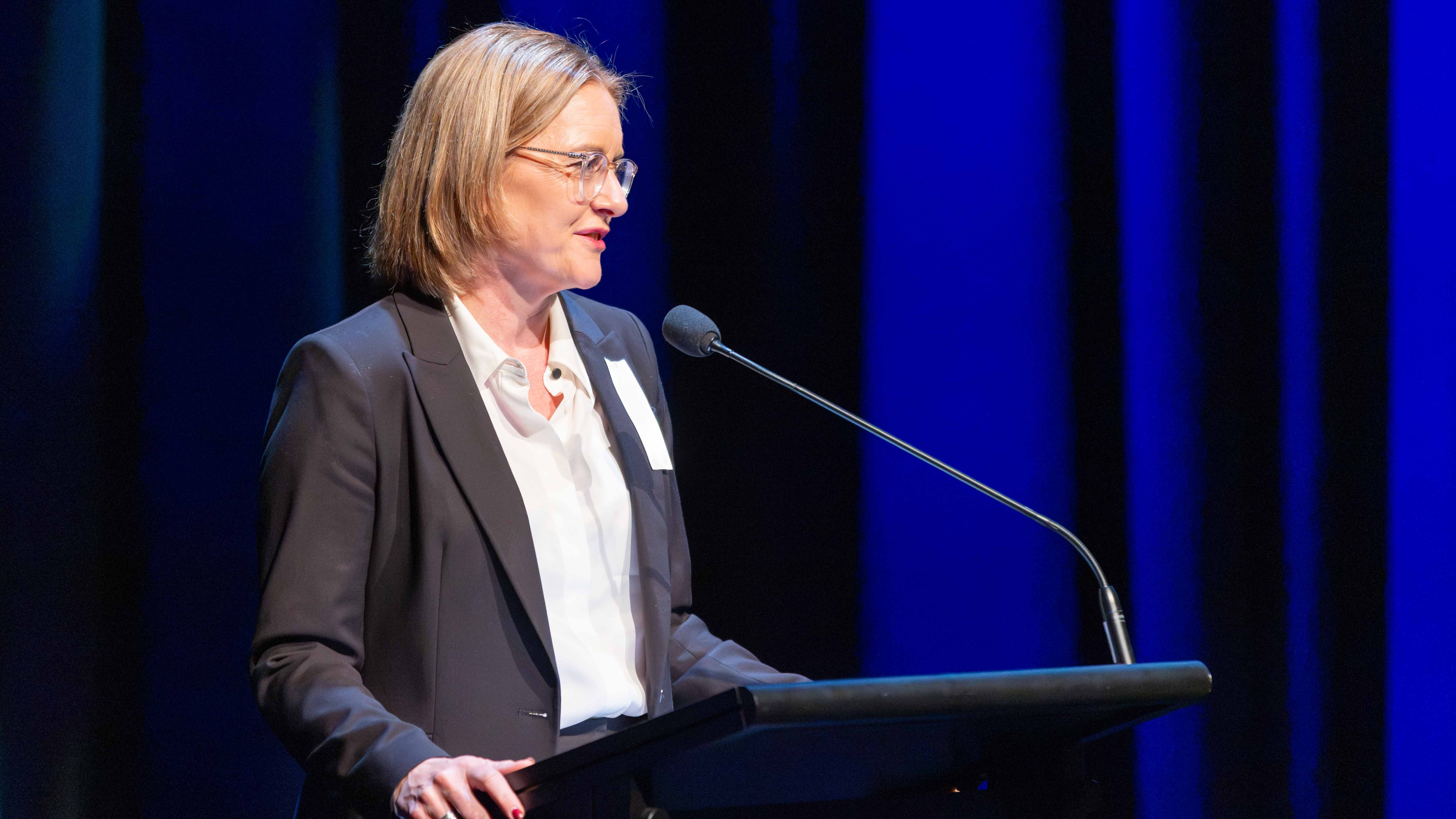 The image shows Hon Jacinta Allan MP speaking at a lectern on behalf of the people of Victoria at the State Funeral Service and sharing some personal memories of Russell