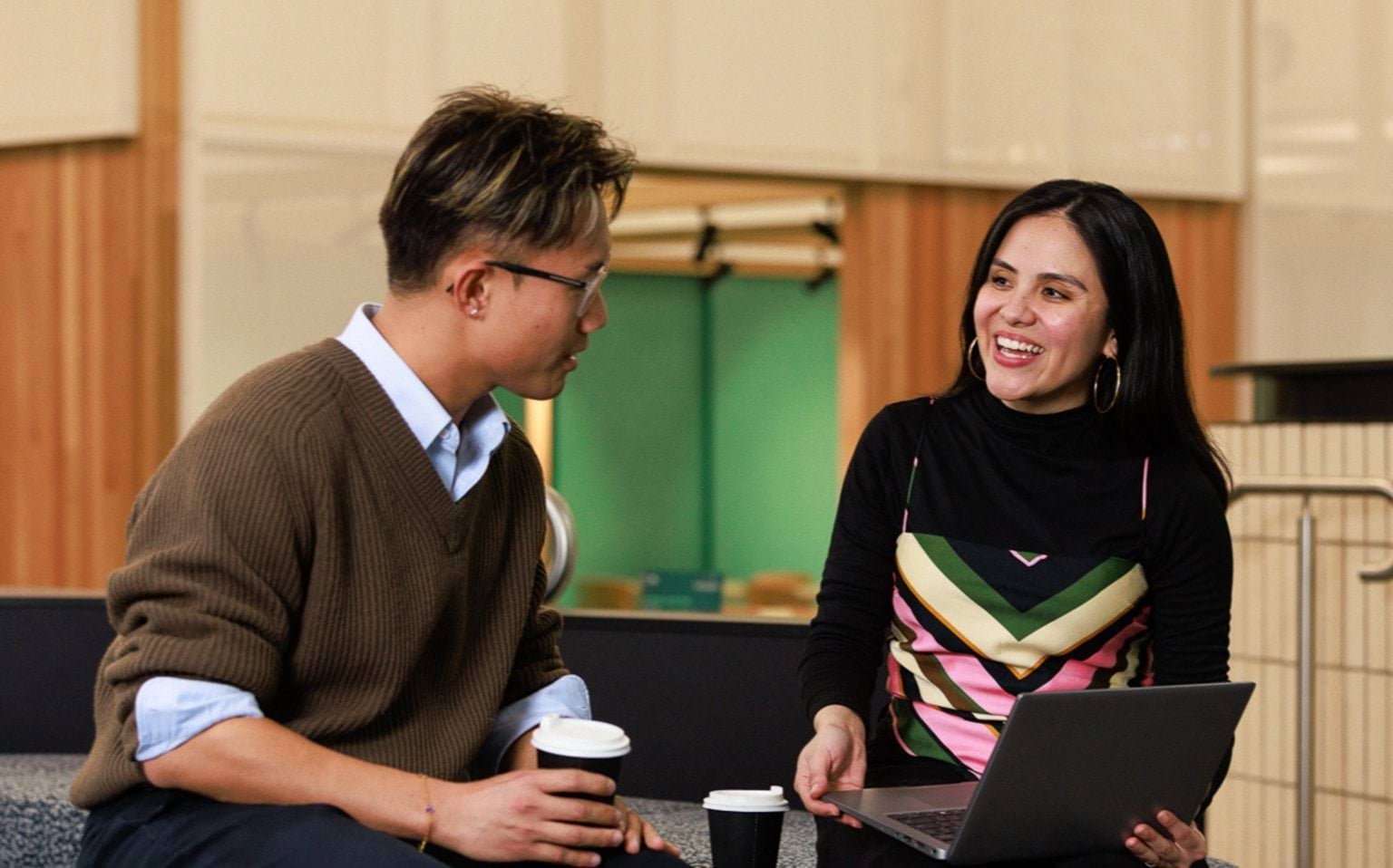 Two people sitting with a laptop in a large room